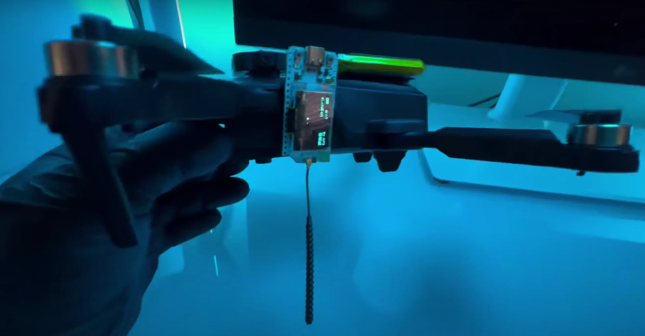 图片展示了一台无人机,其顶部安装了 Meshtastic 设备和电池。Meshtastic 设备固定在无人机的一侧,天线垂直向下,确保飞行过程中信号传输的最佳效果。这种设置演示了将 Meshtastic 设备与无人机结合,改造成移动通信基站的过程,为克服地形障碍和扩大通信范围提供了一种创新解决方案